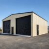 Cream prefabricated steel warehouse by SAMAN with two large black roller-shutter loading bays on an open site.
