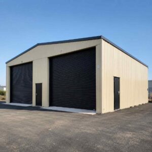 Cream prefabricated steel warehouse by SAMAN with two large black roller-shutter loading bays on an open site.