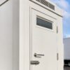 Close-up of a white prefabricated toilet door lock, vent window and steel finish
