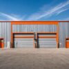 Front view of a grey prefabricated warehouse with orange trim and twin roller-shutter bays.