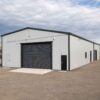 Grey prefabricated warehouse loading bay with a dark roller shutter and concrete access ramp.