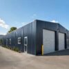 Side elevation of a charcoal prefabricated steel warehouse with windows and grey roller doors.
