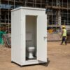 White readymade toilet cabin in use near a labour area on a construction site.