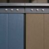 Close detail of prefab wall panel seam showing tight factory joint, weatherstripping, welded steel frame, and colour options