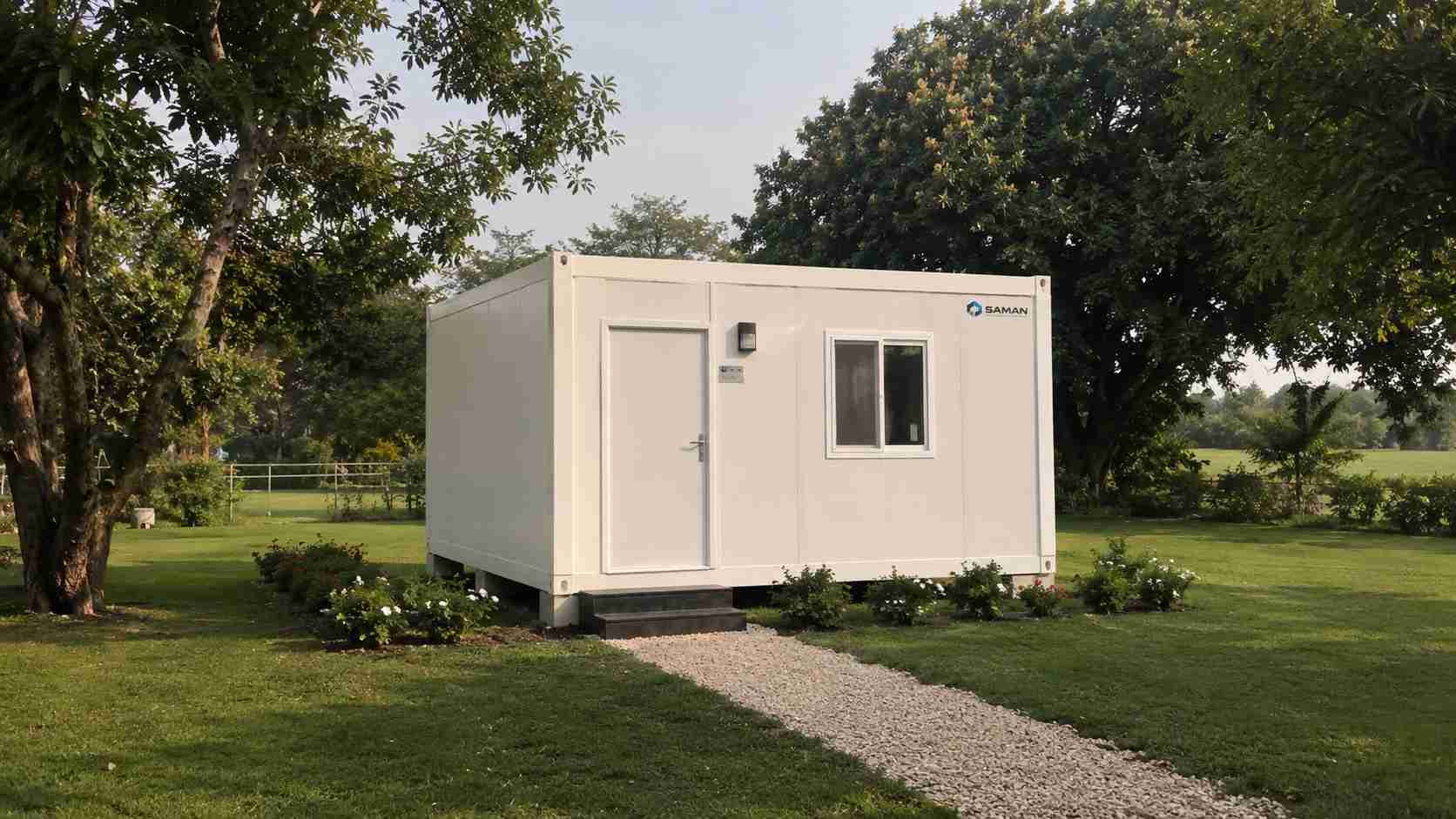 White SAMAN prefab office cabin on a green farmhouse estate with lawn and trees, 400 sq ft unit.