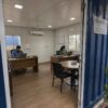 Interior of a 400 sq ft SAMAN prefab office in use, two staff working at desks with meeting corner.