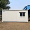 White SAMAN prefab office cabin side profile showing panel seams and roof line, 20×20 ft unit.