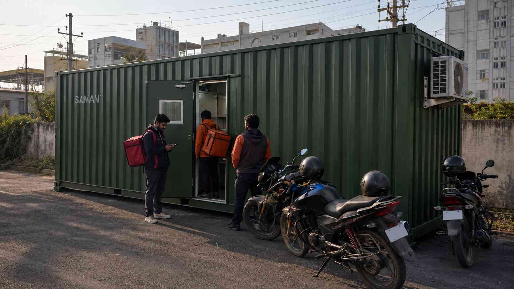 Cloud kitchen operator's SAMAN restaurant food container at an industrial-zone plot in Bangalore with delivery riders waiting outside