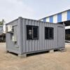 Steel grey 20-ft shipping container office in three-quarter front view at an Indian project site.