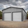 Close exterior of a grey steel prefab building showing wall panels and roller-door openings.