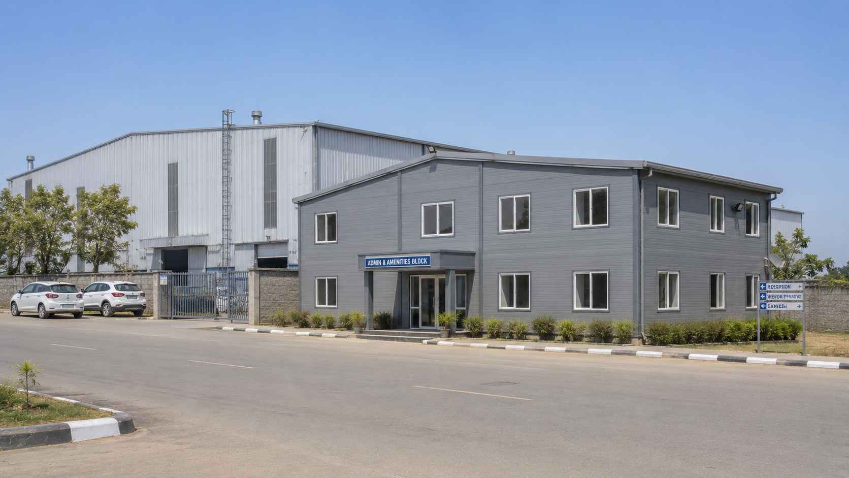Steel grey multi-room steel prefab building beside a factory shed on an industrial campus.