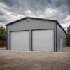 Grey and white steel prefab building, side view, with a personnel door and rooftop solar panels.