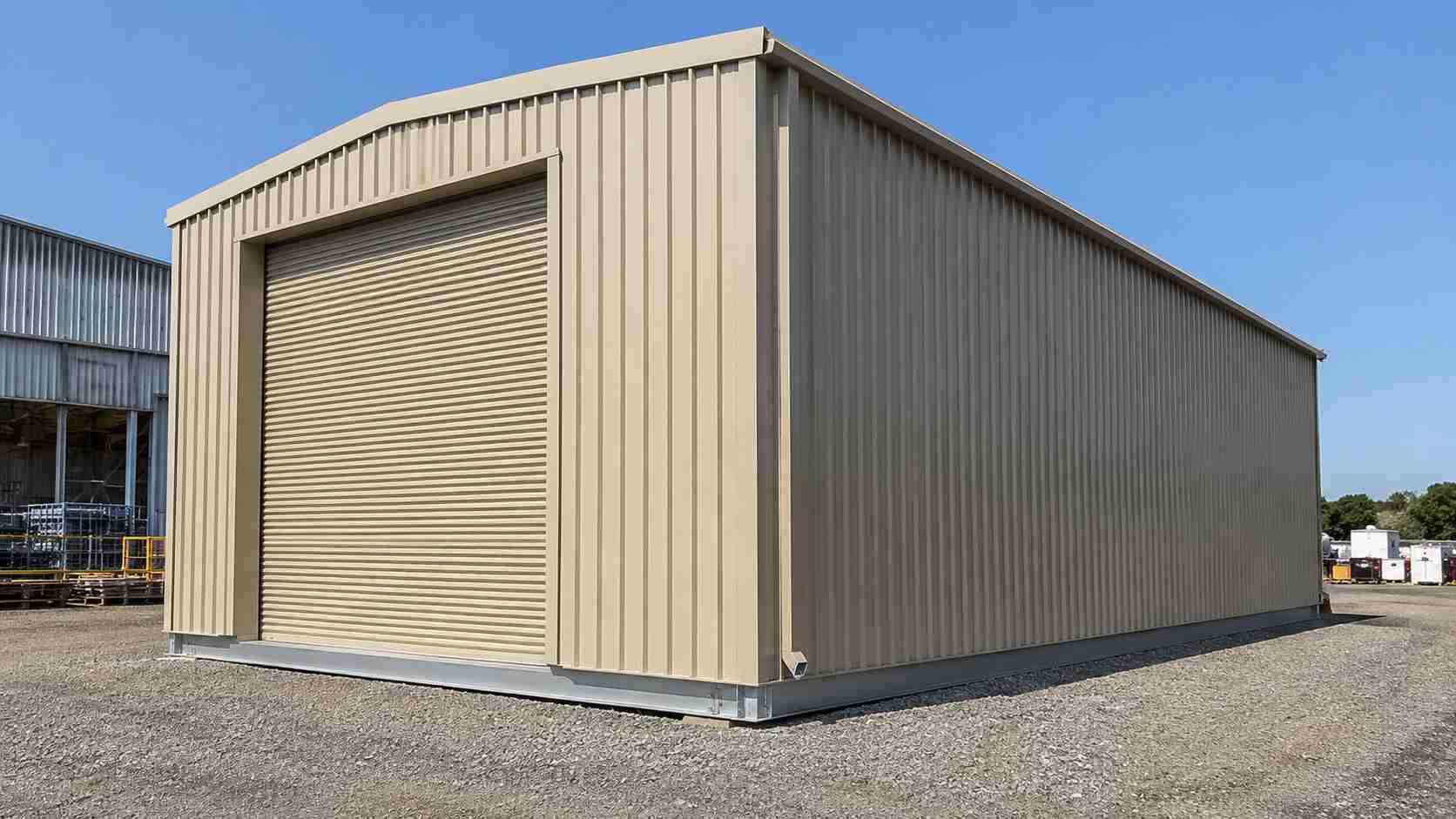 A heavy-gauge structural steel shed in sandstone beige showing a deep ribbed cladding profile