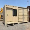 Front-angle view of a Sandstone Beige SAMAN storage container office showing the office-side personnel door with steel step and storage-side dual-lock cargo doors at an equipment rental yard