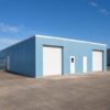 Blue prefabricated storage shed with white roller doors, angled to show depth and side wall.