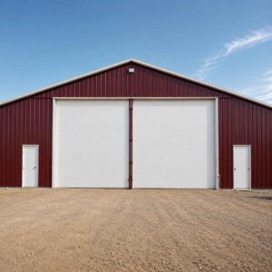 Burgundy 60×36 ft steel storage shed with a large white sliding door on a cleared site.