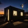 Container office cabin at dusk — interior LED lights glowing through aluminium windows with MS grills, Indian construction site evening
