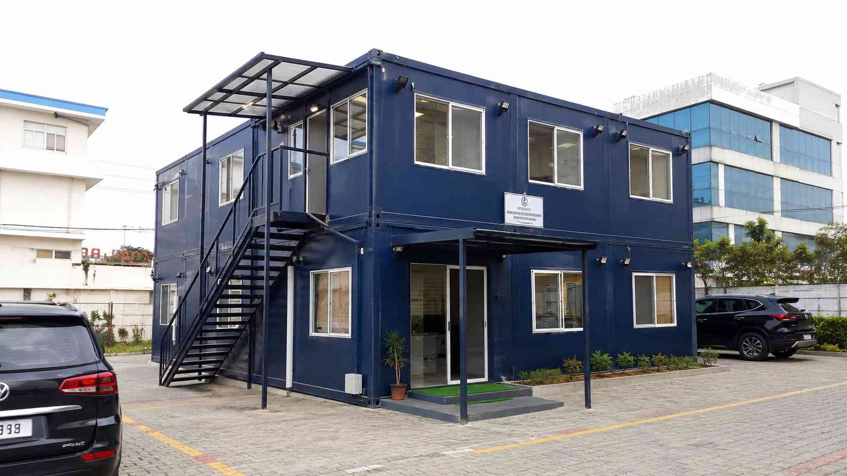 Two-storey Navy Blue modular office building with stacked modules and an external staircase.