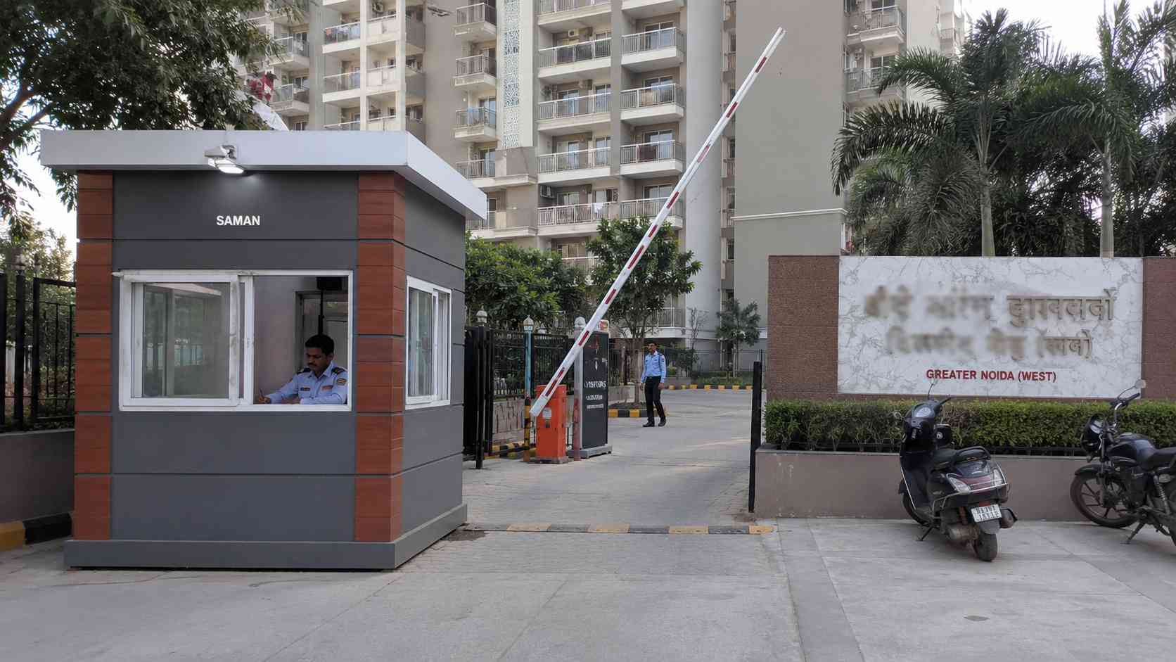 SAMAN 6x6 ft guard porta cabin with Brick Terracotta accent at a Greater Noida West society gate, manned by a security guard.