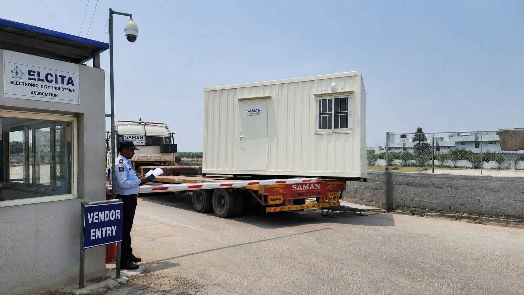 Pure White SAMAN porta cabin clearing an ELCITA vendor gate-pass check at a KIADB Phase 2 plot, Electronic City.