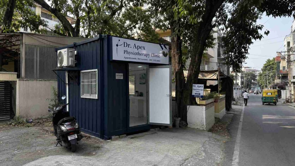 A Navy Blue SAMAN porta cabin set up as a clinic frontage on a Bannerghatta Road plot near Hulimavu, with finished interior visible through the open door.