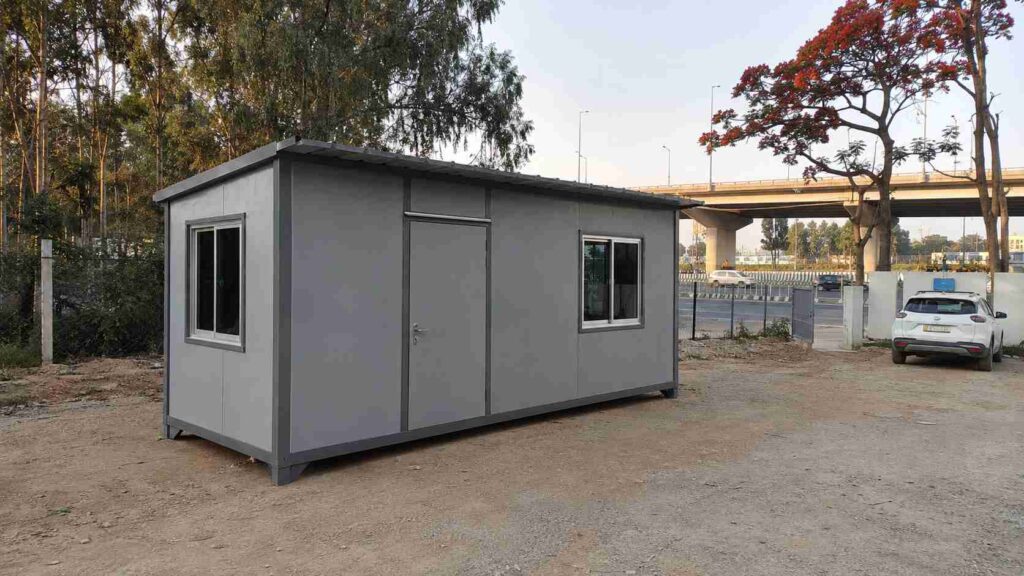 Steel-grey factory-fitted porta cabin installed on a Bellary Road frontage plot near the Hebbal Flyover in North Bangalore.