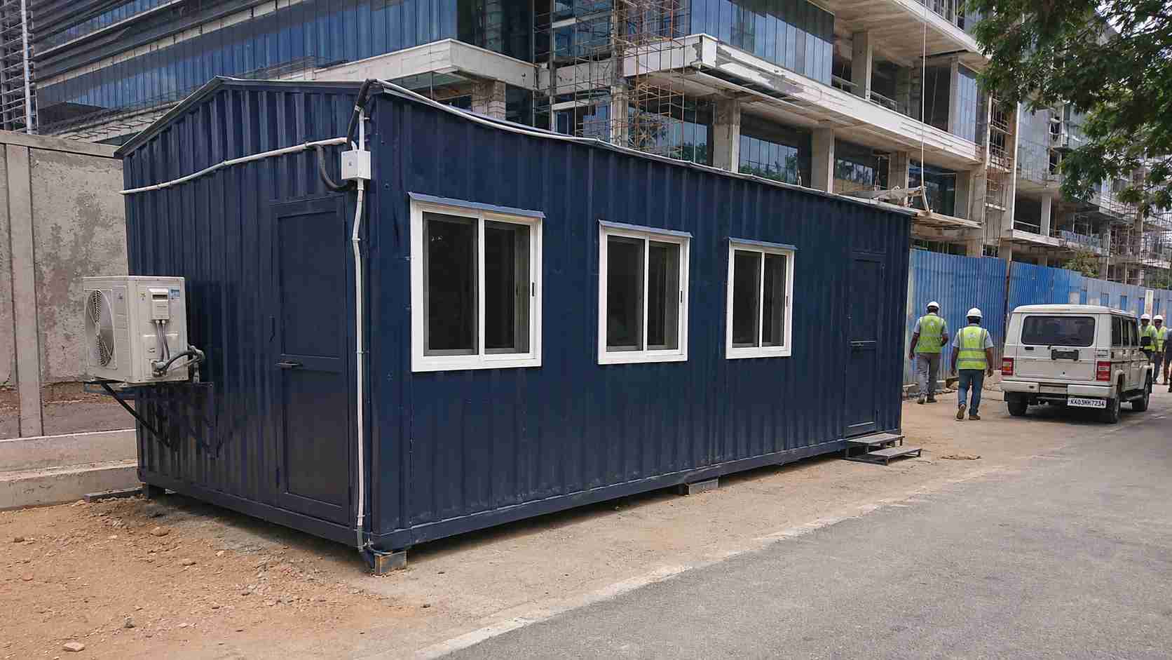 Navy blue multi-room porta cabin serving a Manyata Tech Park fitout contractor at an IT campus on the Thanisandra approach.