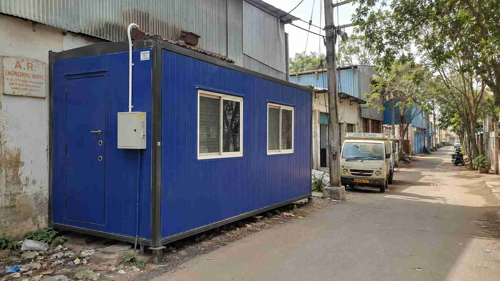 Royal Cobalt porta cabin at an NGEF or ITI Layout heritage-industrial pocket plot in Nagarbhavi serving a small fabrication unit, with secure access door visible.