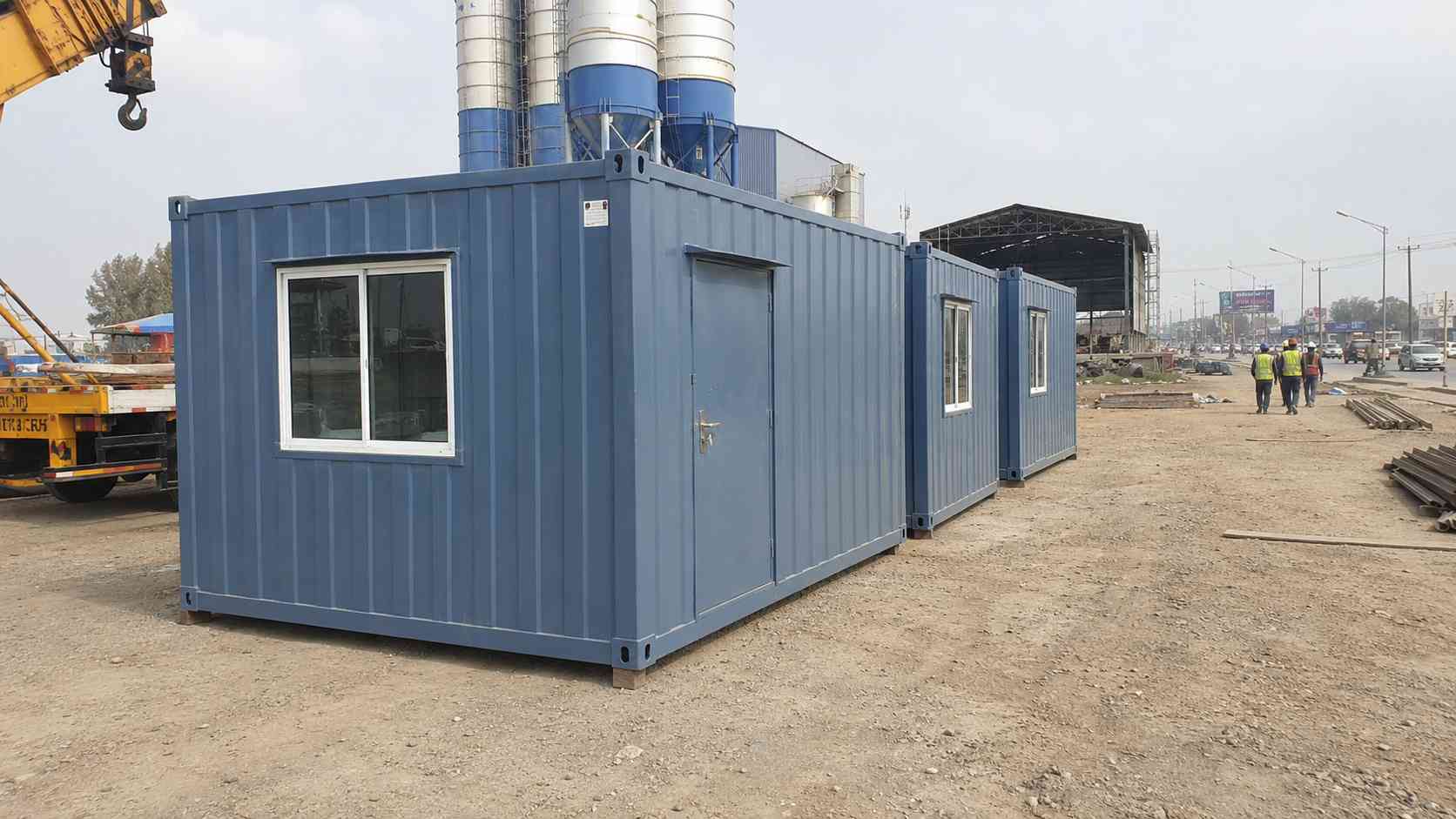 Row of pre-built portacabins for sale in KR Puram, lead unit in Steel Blue, deployed on east-Bangalore industrial corridor site.