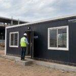 Graphite black SAMAN porta cabin on rent deployed as a site office at an Indian construction site with engineer entering.