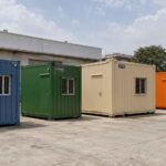 Four SAMAN porta cabins lined up by size at the Bangalore factory yard, from 10×10 ft Steel Blue to 35×11 ft Safety Orange.