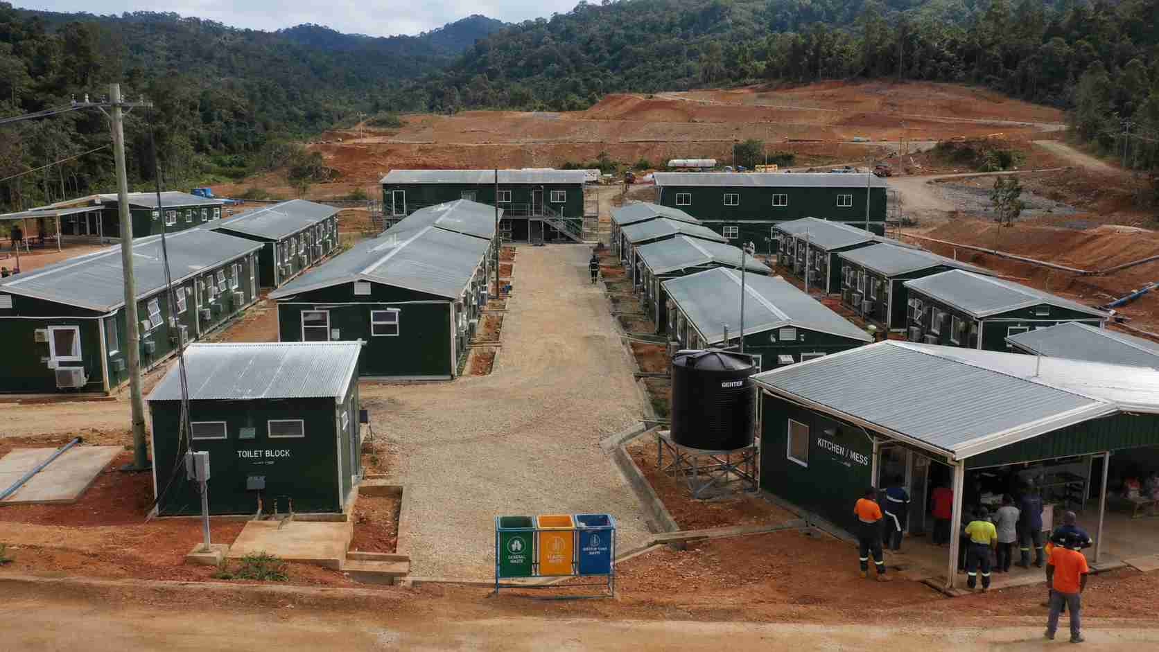Forest-green full labor colony with separate sleeping, toilet and kitchen blocks on a long-term project site.