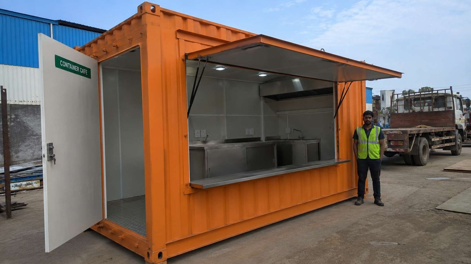 Safety-orange kitchen-ready container cafe at SAMAN's facility, interior showing built-in counter, sink and exhaust.