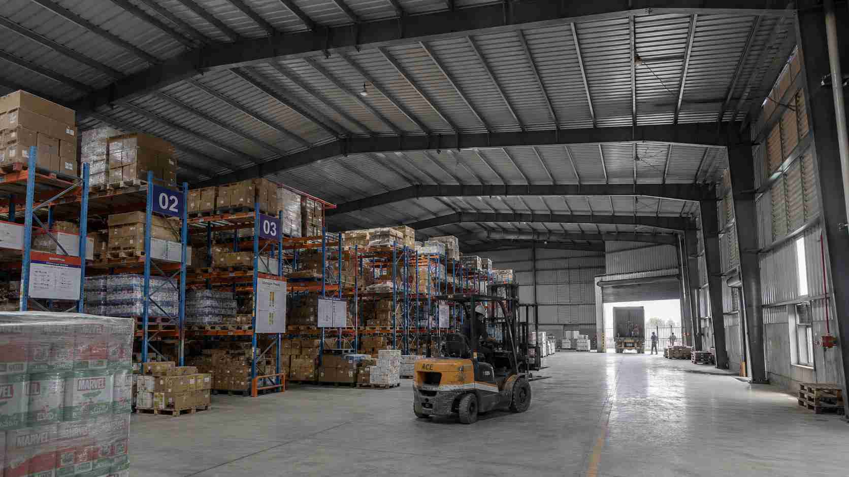 Operational Slate Charcoal PEB warehouse in use with racking, forklift and loading dock.