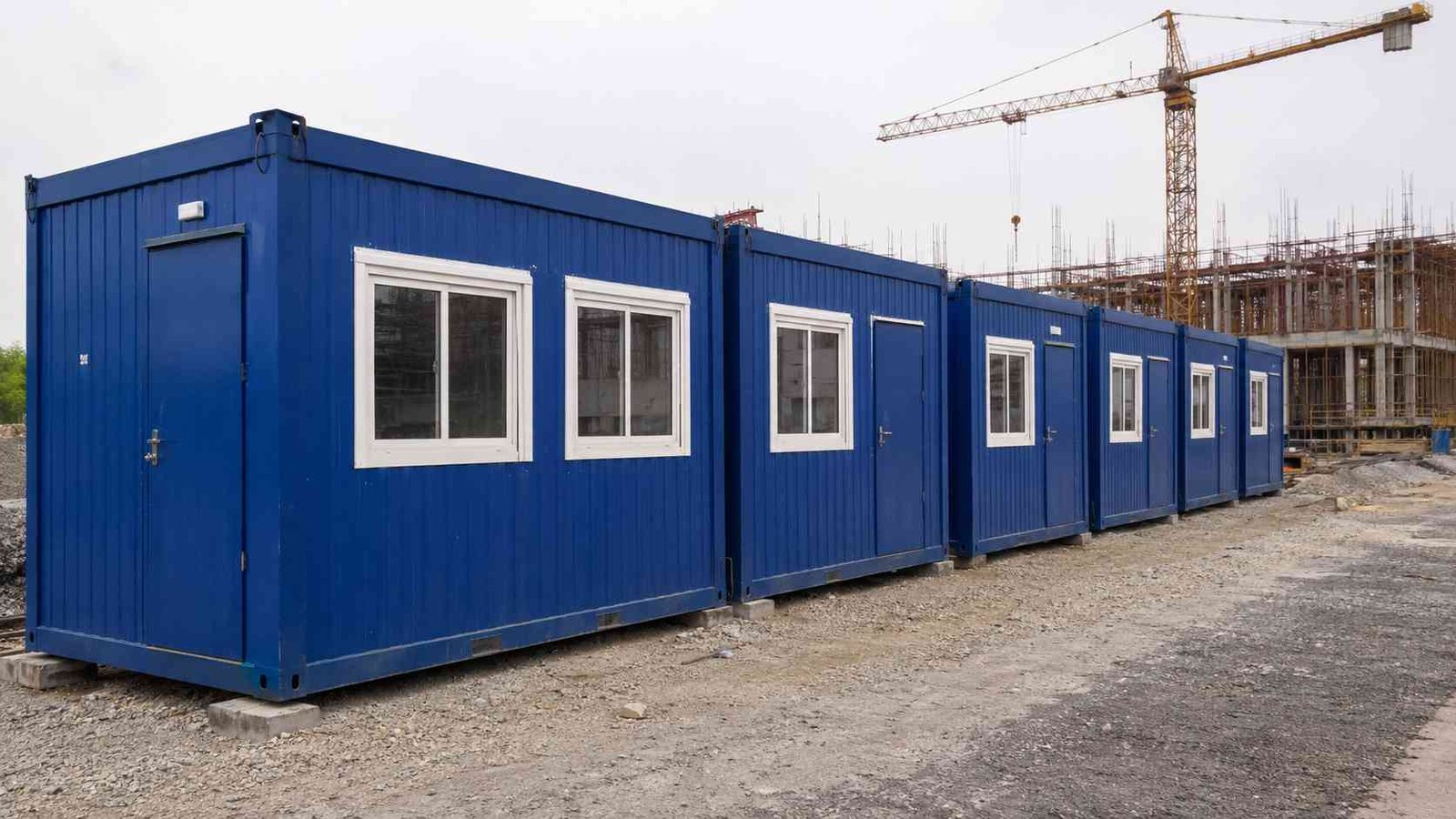 Row of porta cabin types on a construction site, lead unit in Royal Cobalt blue with steel frame. 