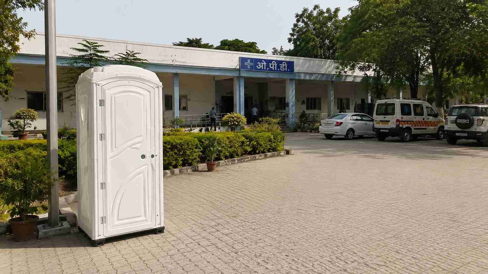 Clean white standalone portable toilet on the grounds of an Indian hospital. 