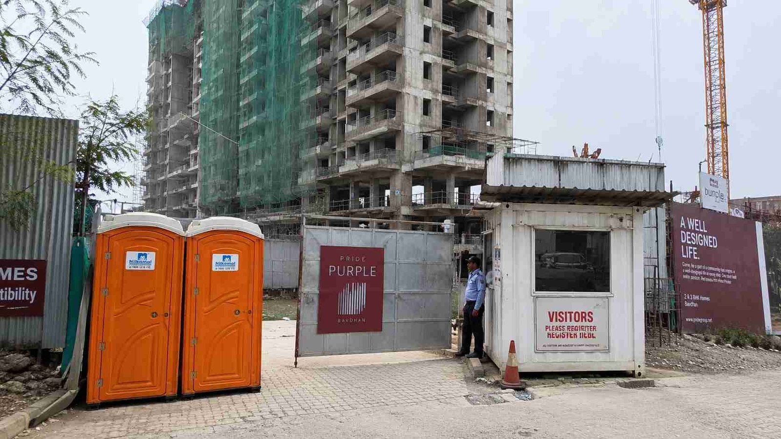 Two Safety Orange portable toilets at the entrance of a residential construction project. 