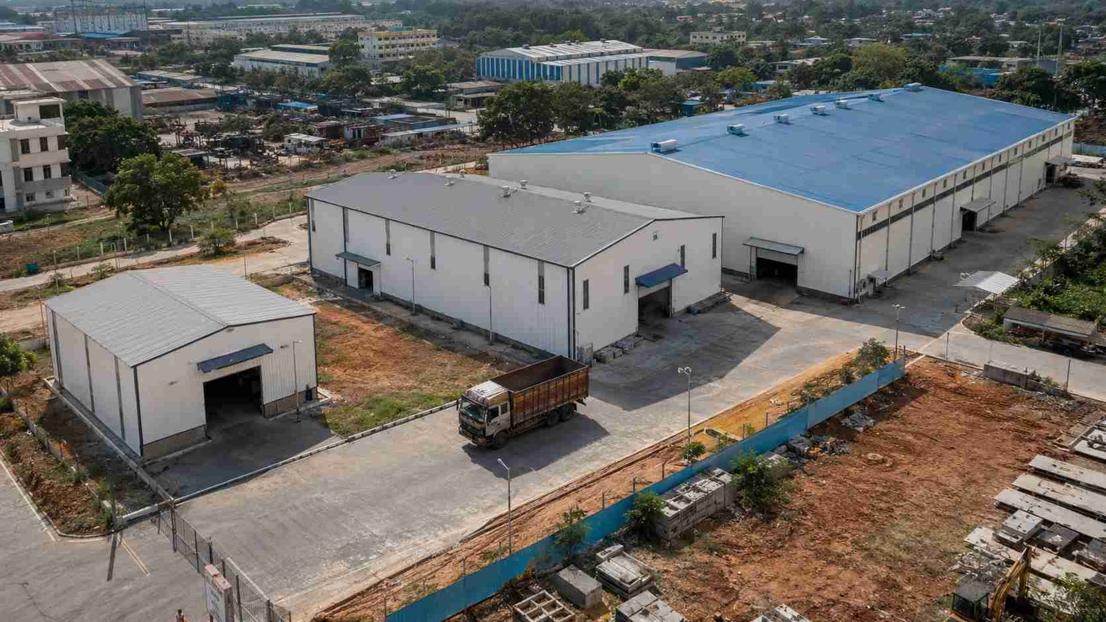 Three pre-engineered steel buildings of different sizes with Pure White cladding on one industrial plot. 