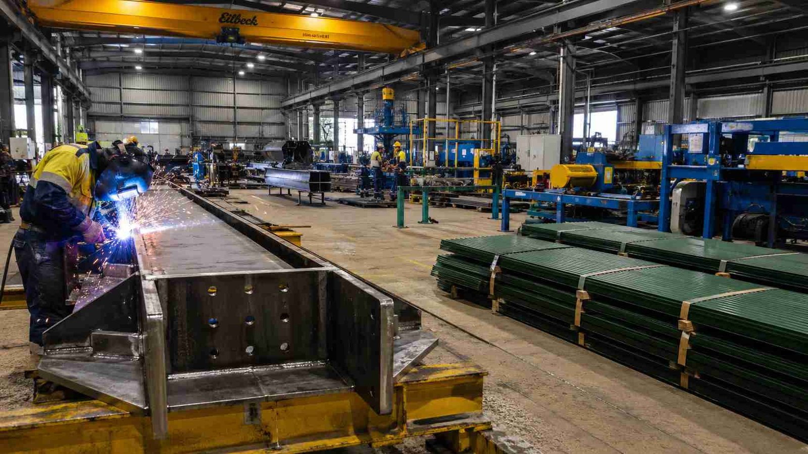 Pre-engineered steel building rafters being fabricated in-house beside Forest Green roof sheets at SAMAN's factory.