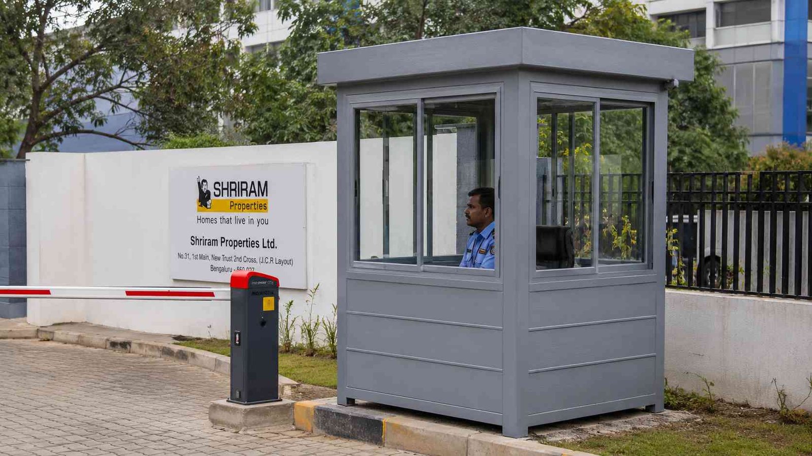 Steel grey SAMAN security cabin with 360-degree windows at a commercial compound gate in India.