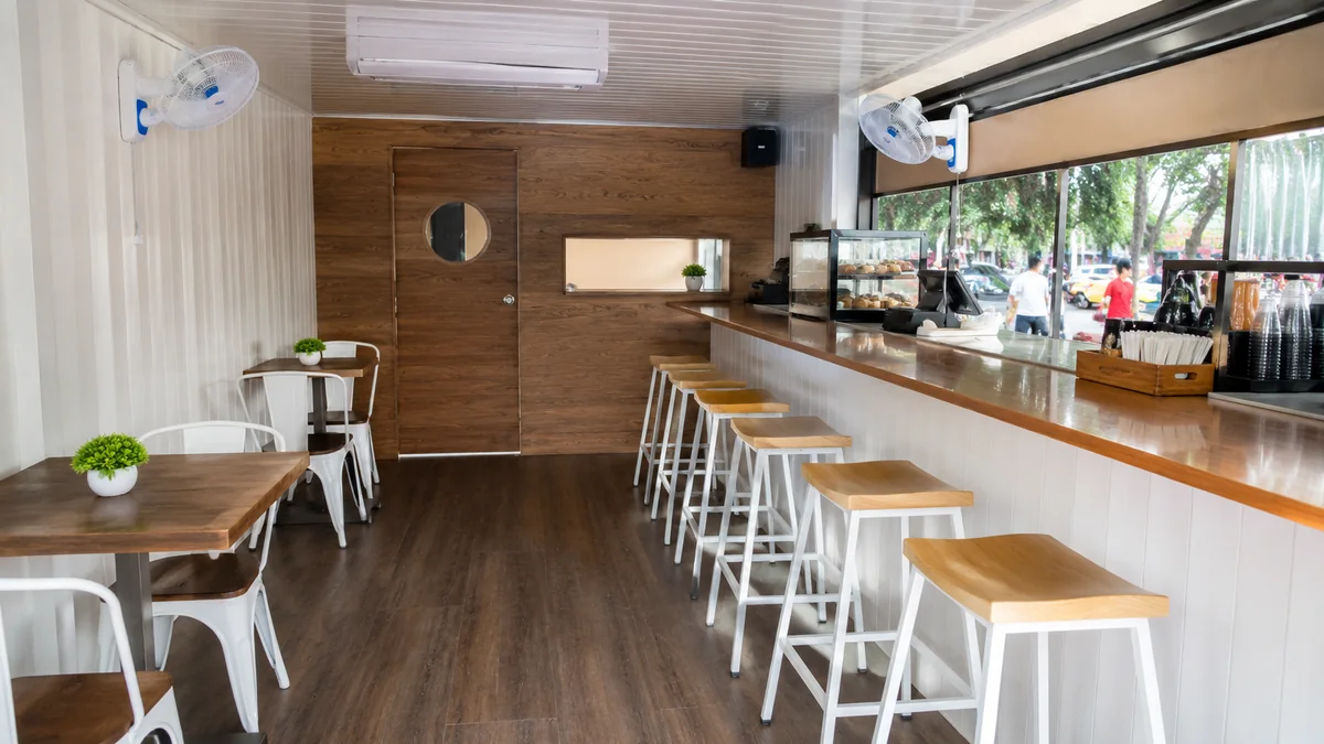 Clean interior of a new container cafe with service counter and compact seating.