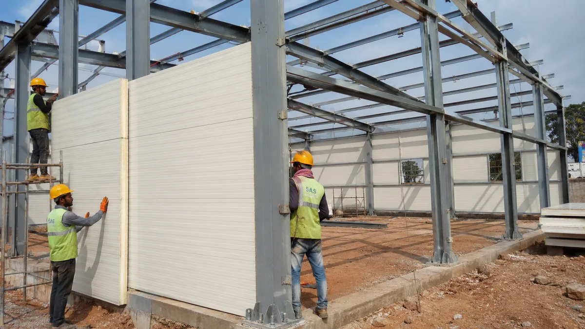 Bolted MS steel shed frame with insulated panels being fixed during on-site assembly in Bangalore