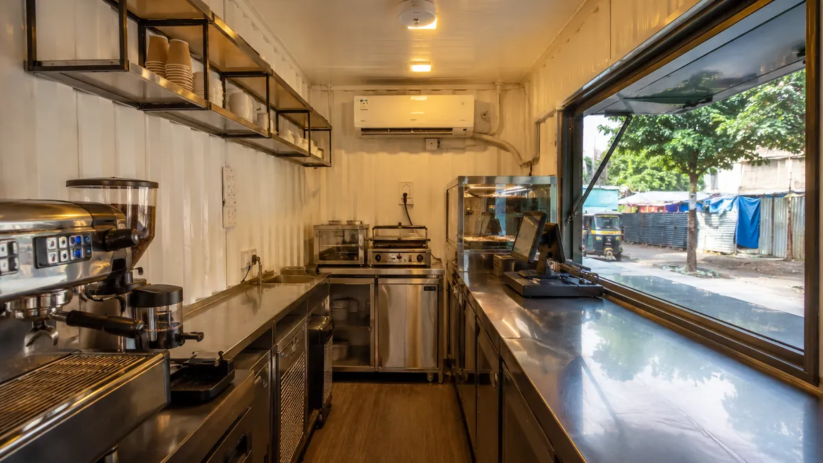 Clean interior serving setup of a new kitchen-ready container cafe for a Central Delhi outlet.