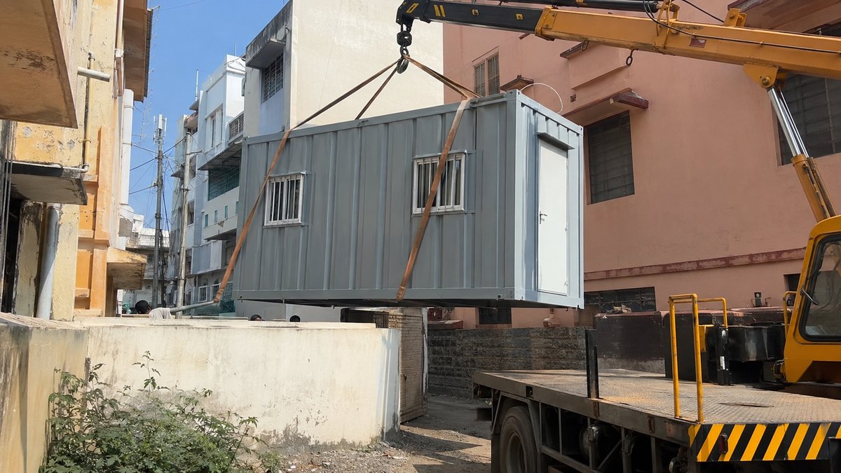 New steel porta cabin being craned into place on a narrow central Bengaluru lane
